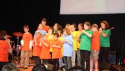 Kinderchor in bunten T-Shirts singt und gestikuliert