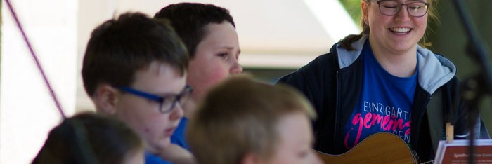 Jugendliche spielt Gitarre, begleitend zum integrativen Kinderchor, Auftritt beim Protesttag zur Gleichstellung von Menschen mit Behinderung