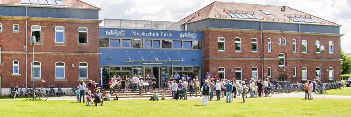 Gebäude der Musikschule Fürth im Südstadtpark, davor viele Menschen im Sonnenschein 